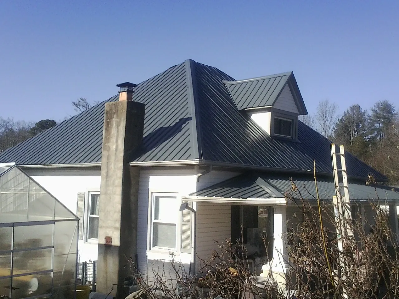 Dark blue standing seam metal roof on a white farmhouse with dormer — Slate & Tile Roof Repair by Roofing Brothers in Ridley Park