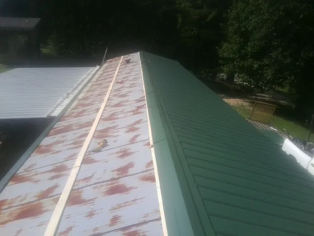 Old rusted panels beside newly installed green metal roofing — Wind Damage Roof Repair by Roofing Brothers in Ridley Park