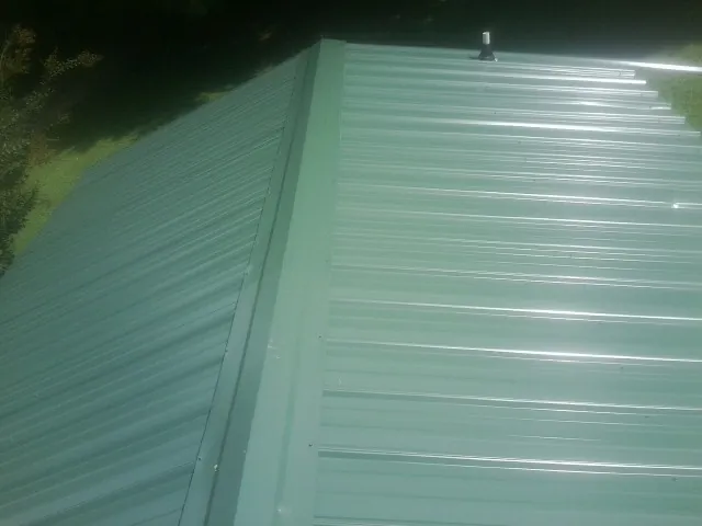 New green metal panels meeting at the ridge of a roof — Flat Roof Repair work by our crew in Ridley Park