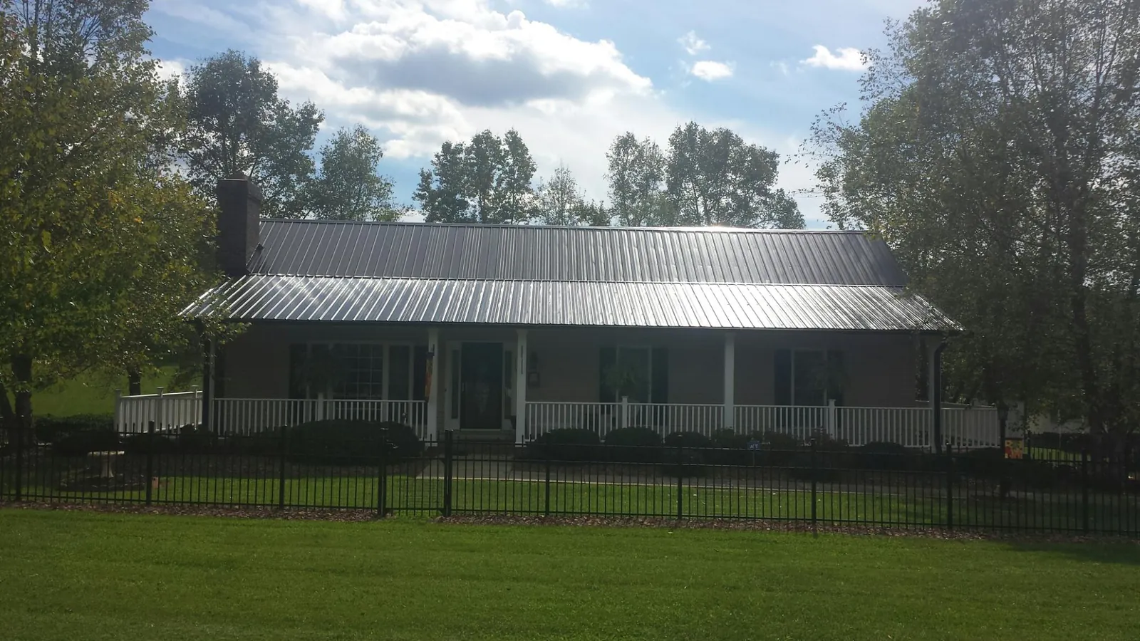 Gray metal roof on a brick ranch with a full width front porch — Gutter Guard Installation work by our crew in Ridley Park
