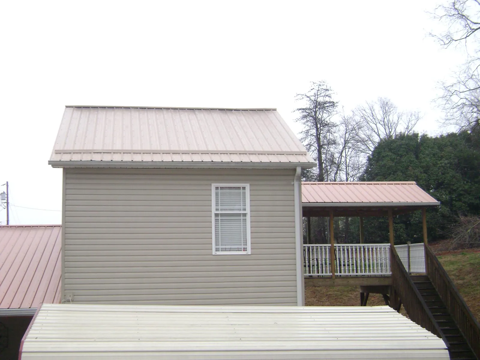 Tan metal roofs on a two story addition and attached porch, from a Roof Replacement job in Ridley Park