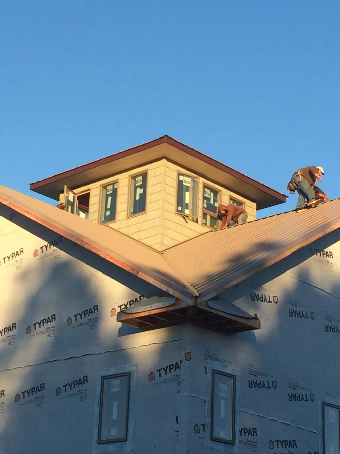 Roofers working around a rooftop cupola on a new metal roof at sunset — Roof Waterproofing in Ridley Park by Roofing Brothers